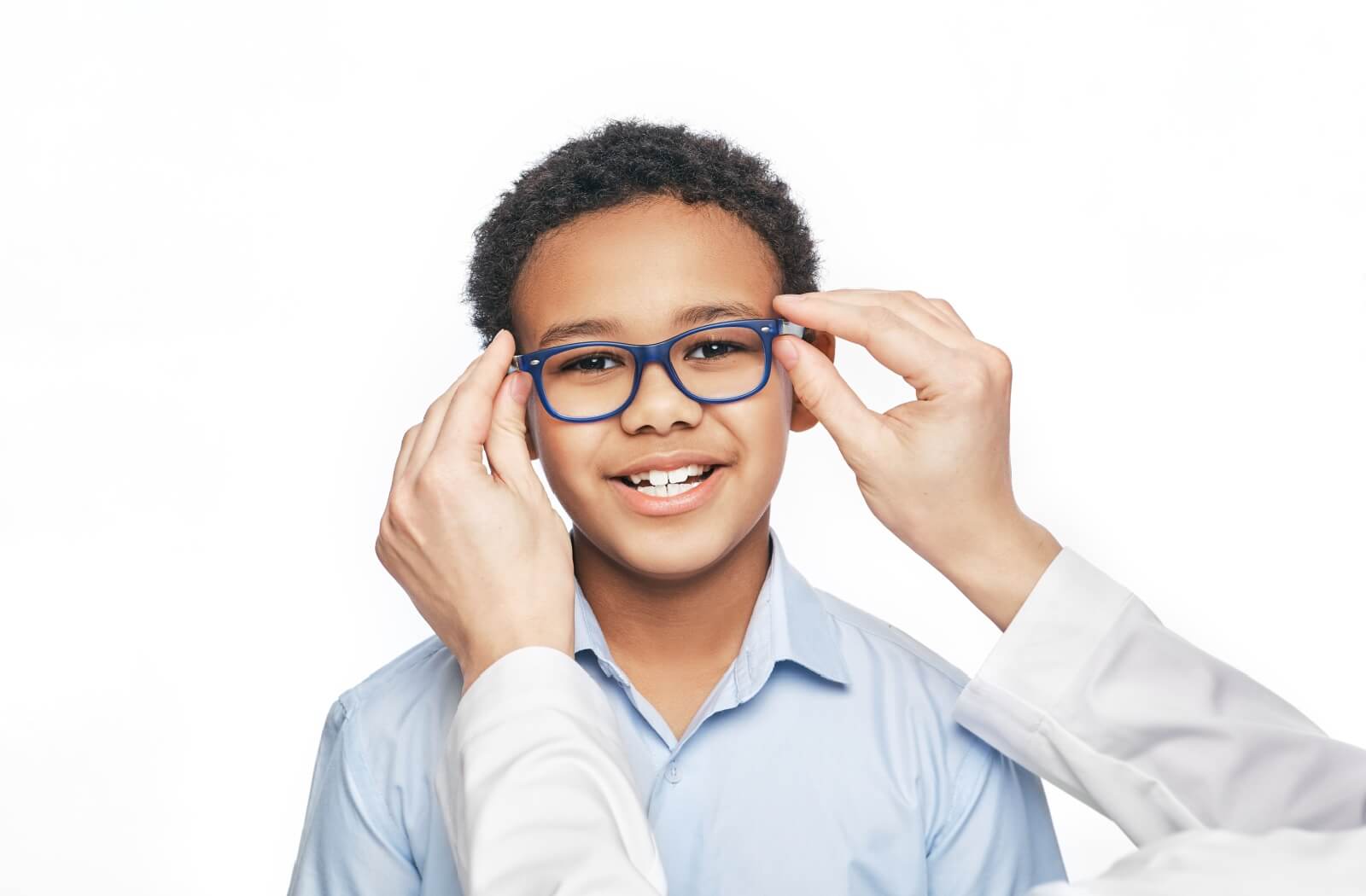 A smiling young boy being fit with a pair of glasses for his myopia.