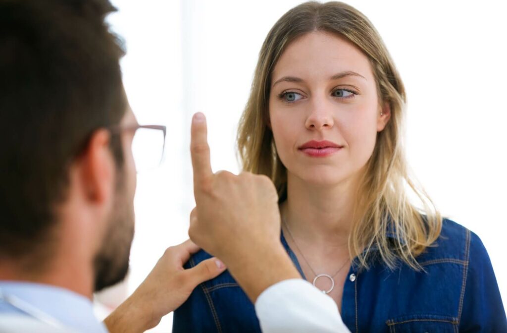 A person follows their eye doctor's finger with their eyes during an eye exam.
